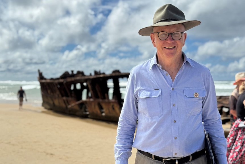 Man in front of a shipwreck.