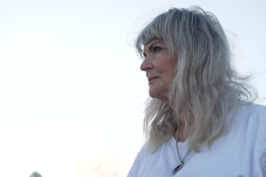 Blonde woman smiles holding bowl with microphone.