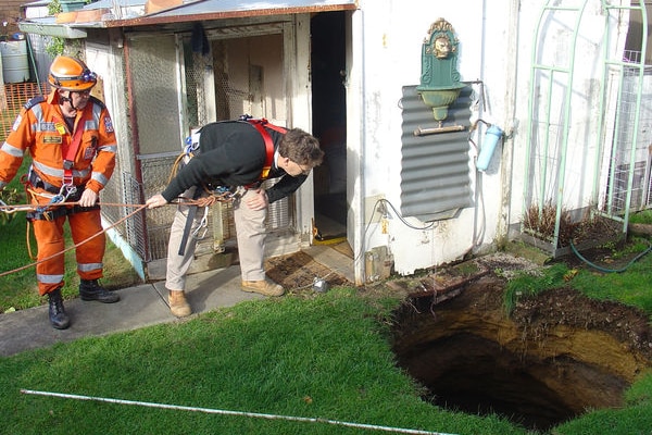 ses workers lower themselves into a sinkhole