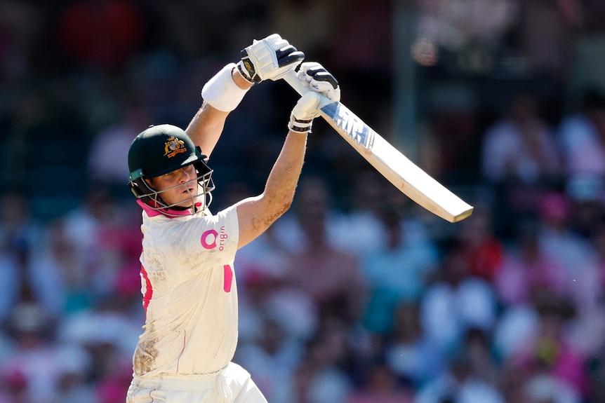 Australia batter Steve Smith finishes a drive with his bat high in the air.
