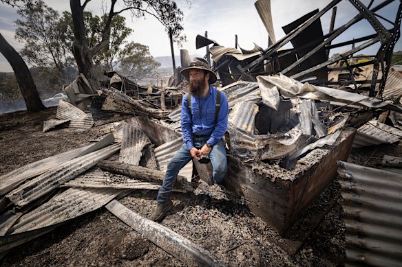David Foley sits among the ruins of buildings in the tiny goldfields town of Harcourt. Fifty homes were lost in the town.