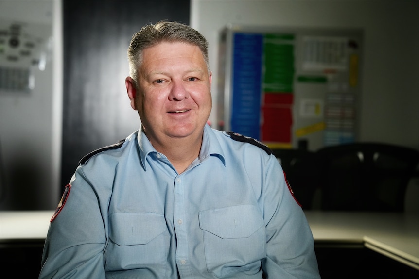 Rohan sits and smiles wearing his police uniform.