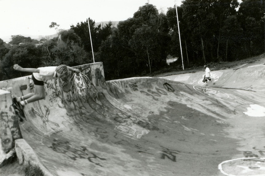 A skateboarder on a vert wall. 