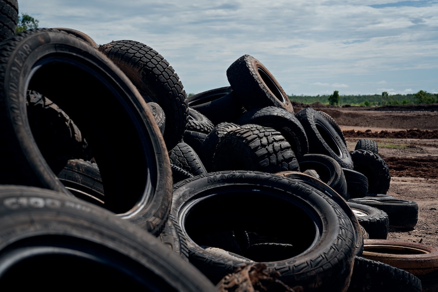 A pile of old tyres sitting on an empty lot.