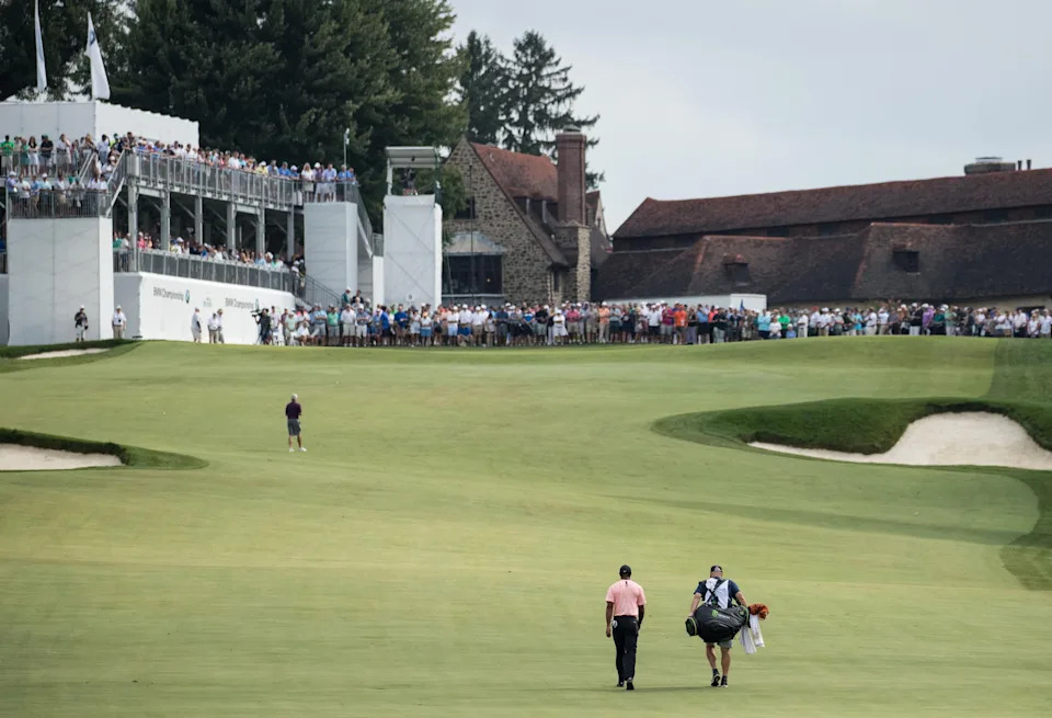 General view as Tiger Woods hands and his caddie Joe LaCava walk up the 9th fairway during the second round of the 2018 BMW Championship golf tournament at Aronimink Golf Club.