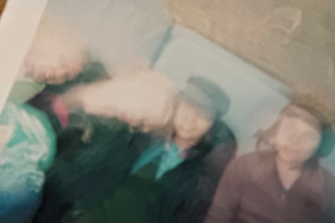 An image of a blurry polaroid picture depicting Yasmine Ghoniem with three friends sat down together.