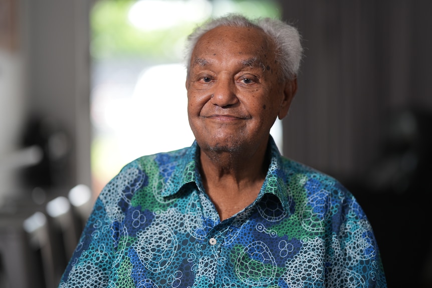 Fram Ahmat sits smiling while wearing a colourful shirt. 