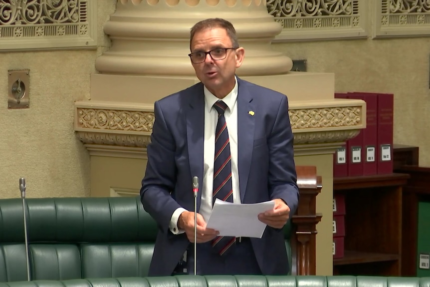 A member of parliament on his feet in the chamber to ask a question while holding a piece of paper