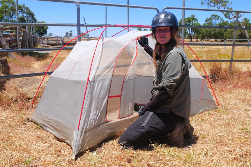 woman kneeling next to tent zipping it up