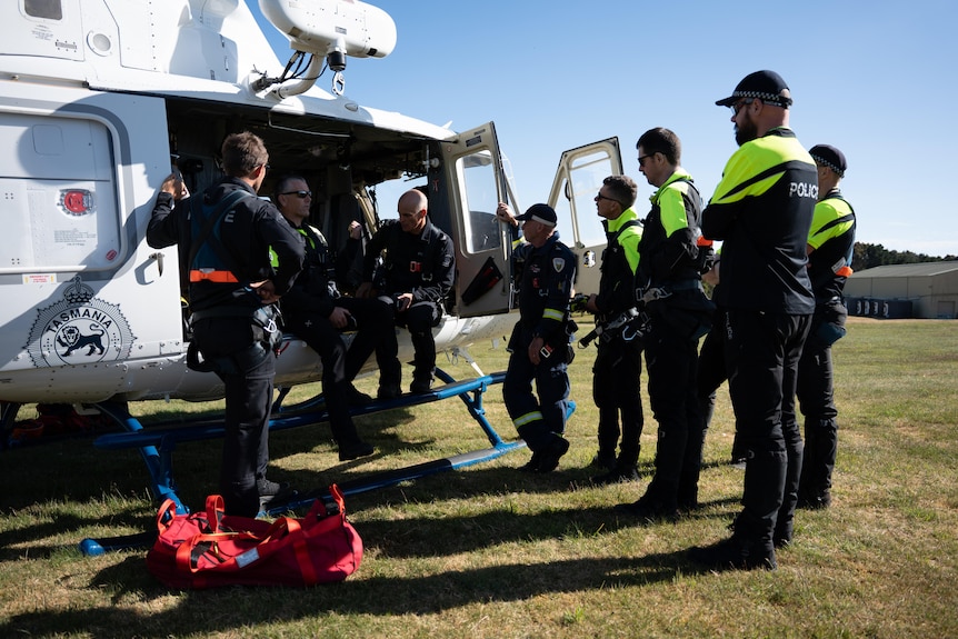Search crew next to a helicopter.