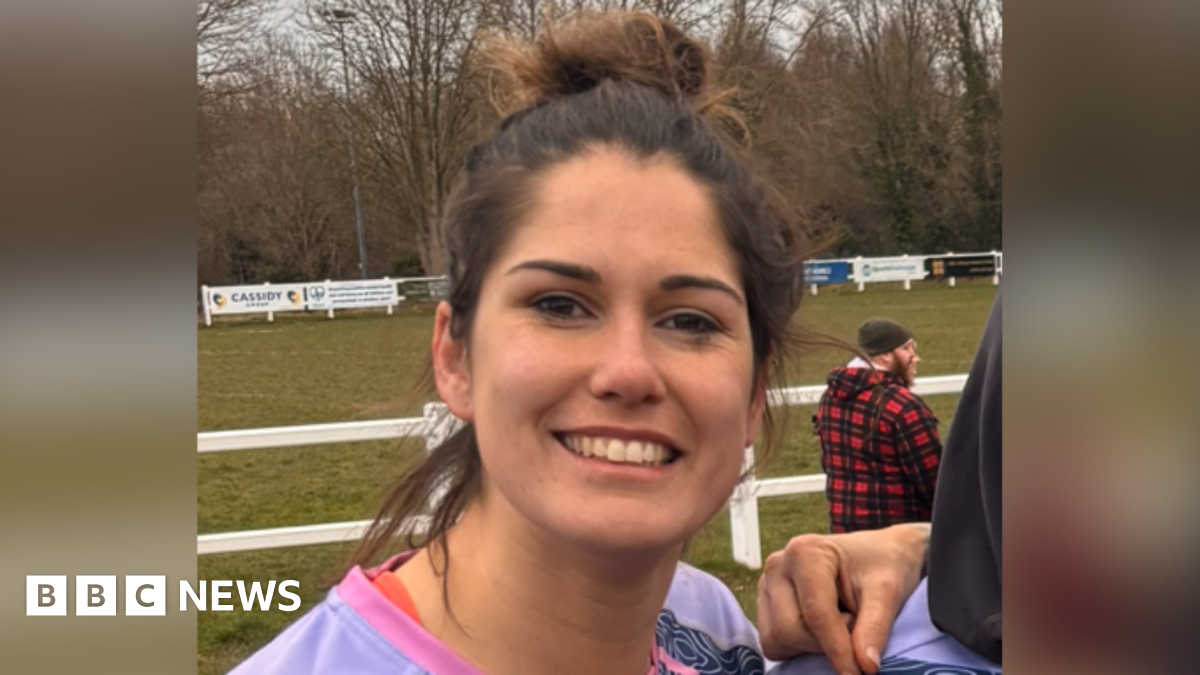 A picture of Annette Bevan in her rugby kit, stood in front of a rugby pitch.
