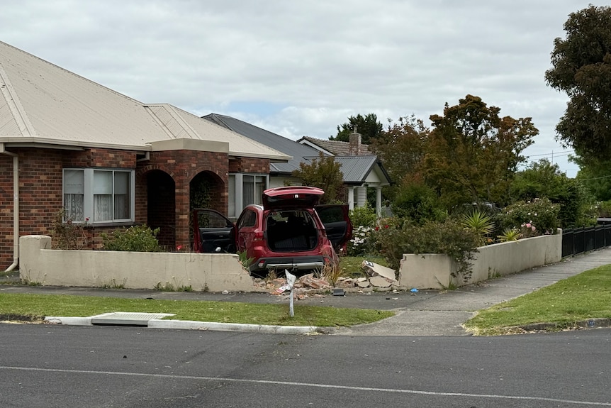 A red SUV crashed through short brick wall of front yard on corner property.