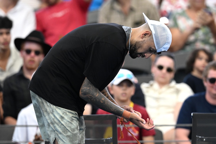 Nick Kyrgios looking at the strapping on his wrist