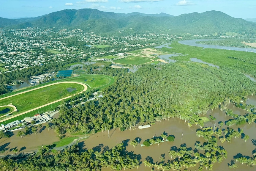 A drone shot of a river exceeding its banks surrounded by greenery 