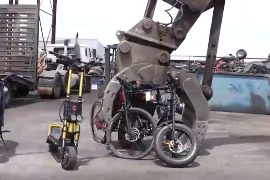 Electric bikes being crushed by heavy machinery.