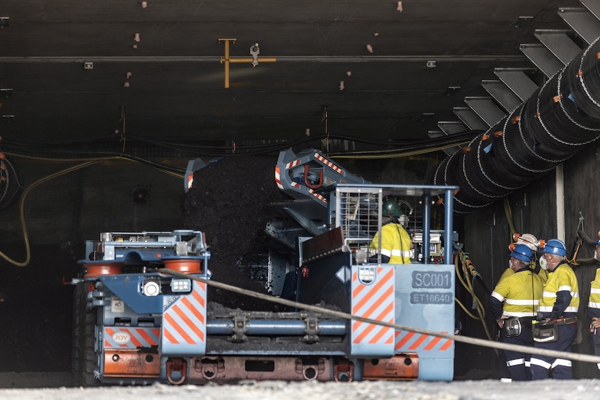 A photo of mining equipment and workers in an underground mine