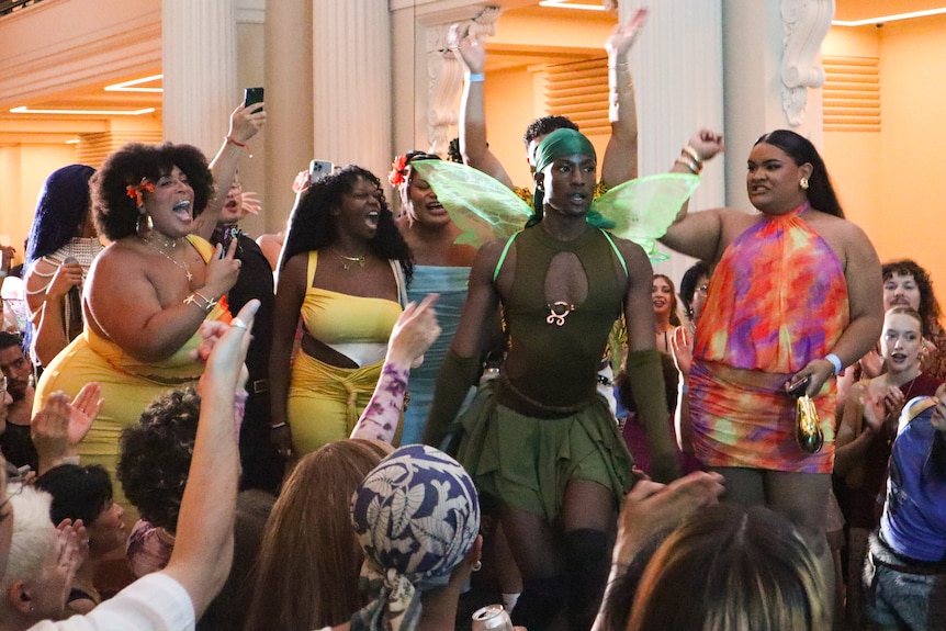 A person wearing a green fairy costume surrounded by other people celebrating them.
