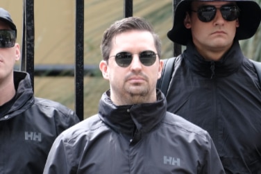A man wearing dark sunglasses and a black jacket.