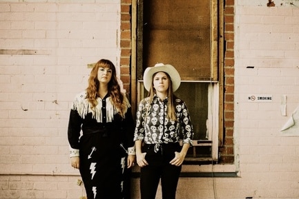 man and woman side by side. the woman wears a cowboy hat.