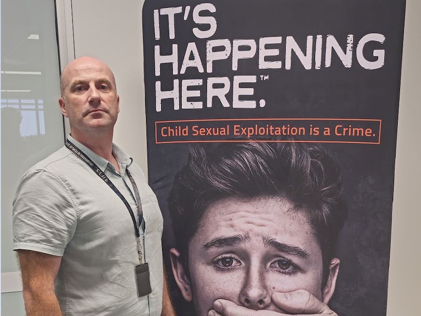 Man standing next to large anti-abuse poster
