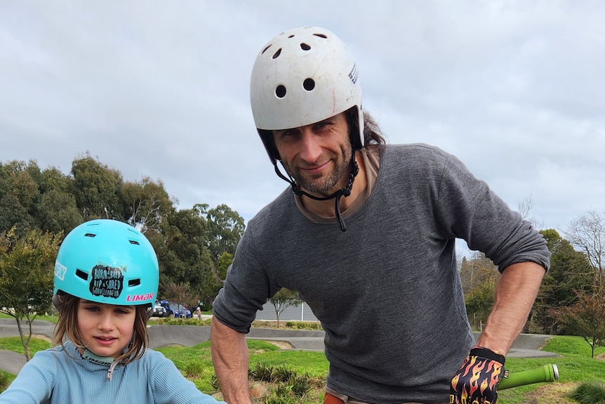 A mna stands next a young girl wearing BMX gear