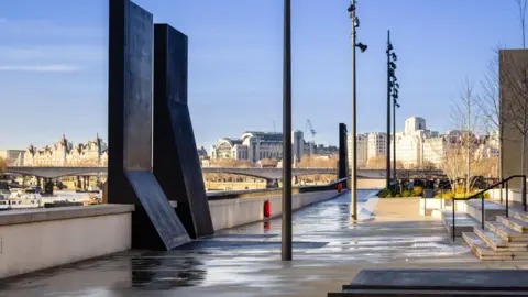Tideway A smooth path and steps by a river, with a black oblong sculpture in the foreground and some concrete steps in view.