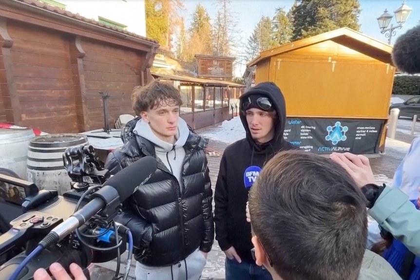 Two young men, surrounded by cameras, journalists and microphones.