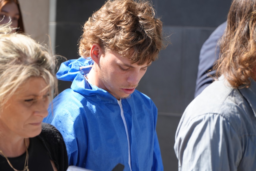 A young man in blue walking with head down 