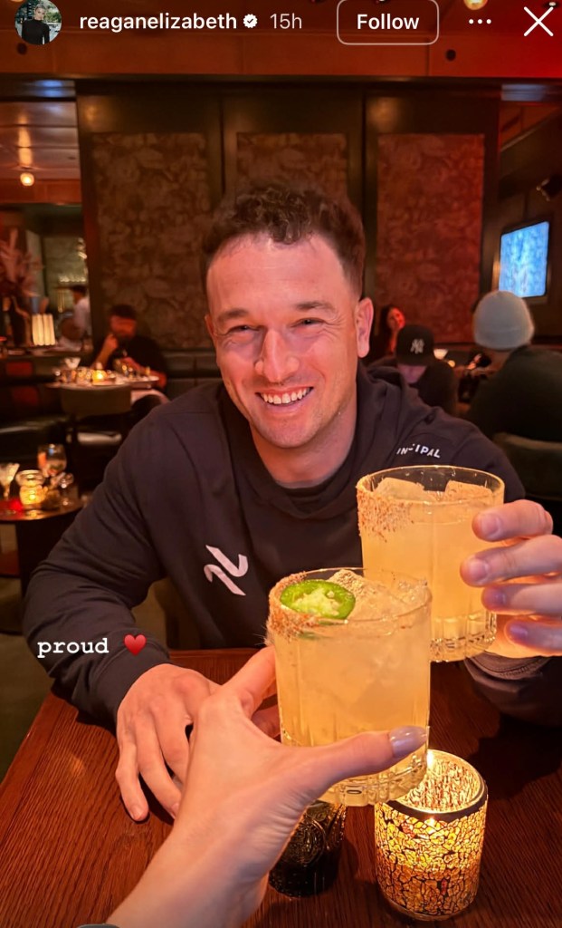Alex Bregman smiling and holding a cocktail while toasting with a woman.