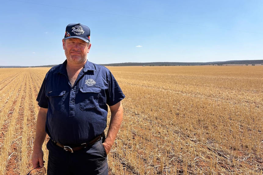 A man stands in a large paddock.