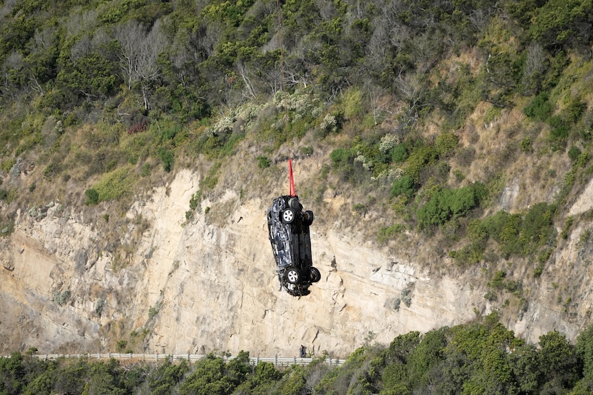 A car being winched from the sea by a helicopter along the Great Ocean Road.