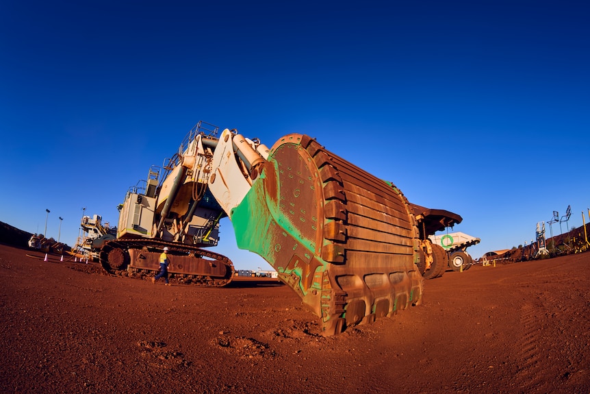 A wide angle shot of a large, electric excavator operating in the dirt of a Pilbara mine site.