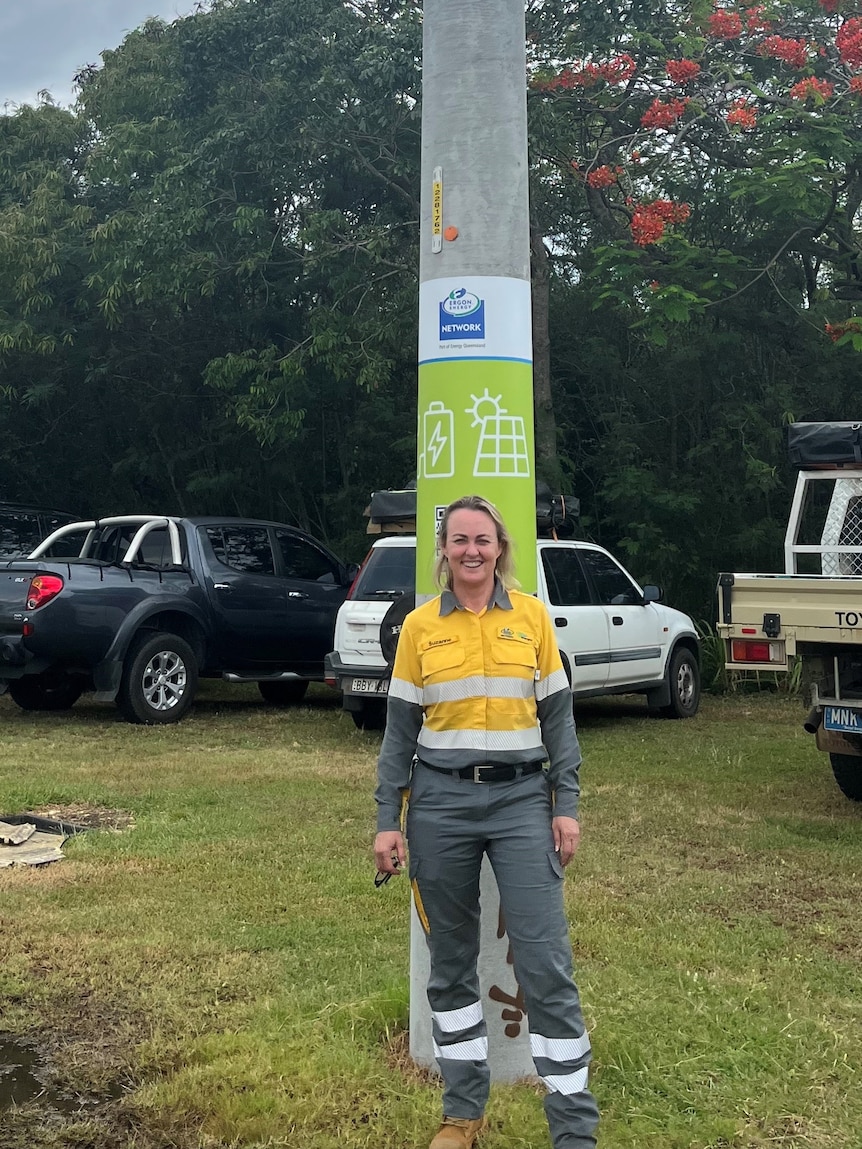 a woman stands in front of an electricity pole