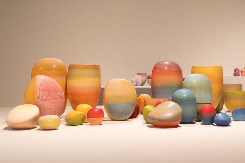 Clusters of colourful porcelain pieces on display in art gallery space