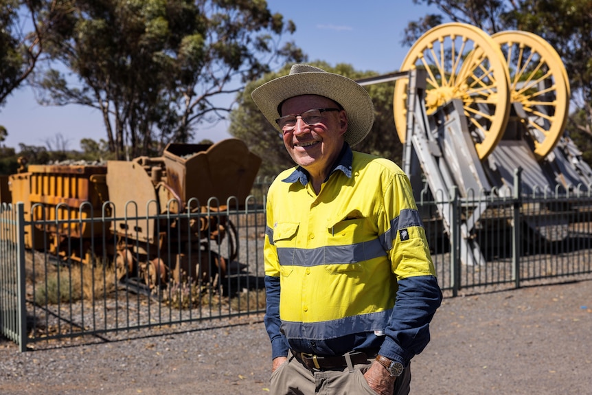 A man in high-vis workwear standing in front of old mining relics on display at a museum.  