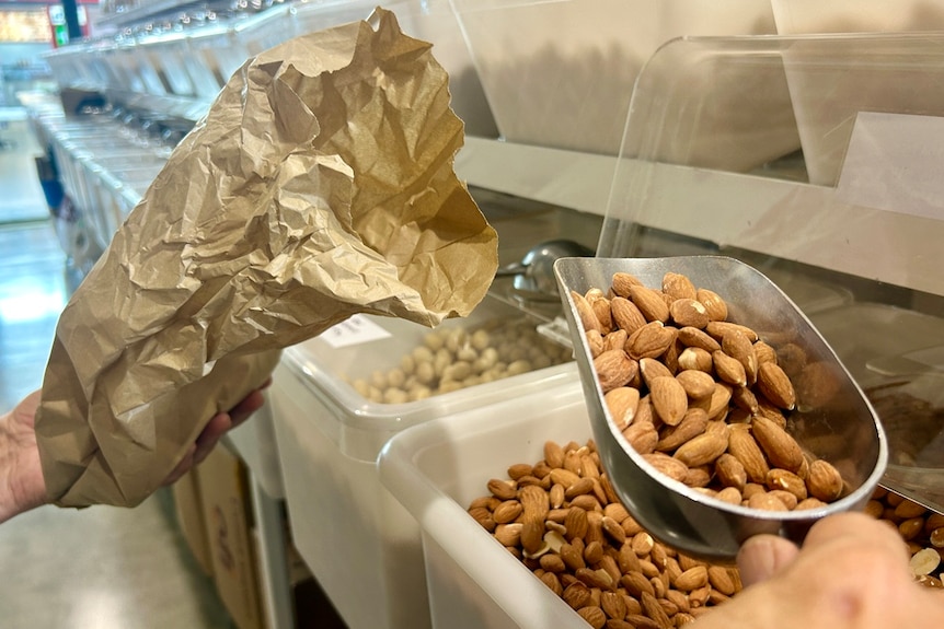 scoop of almonds being put into a paper bag