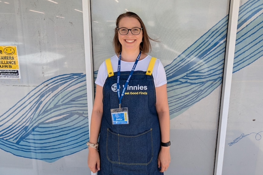Young lady standing out the front of the store wearing a lanyard and apron