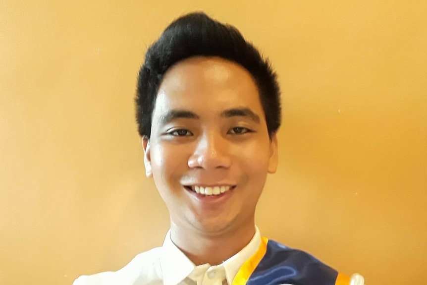 A young, dark-haired man smiles for a selfie.