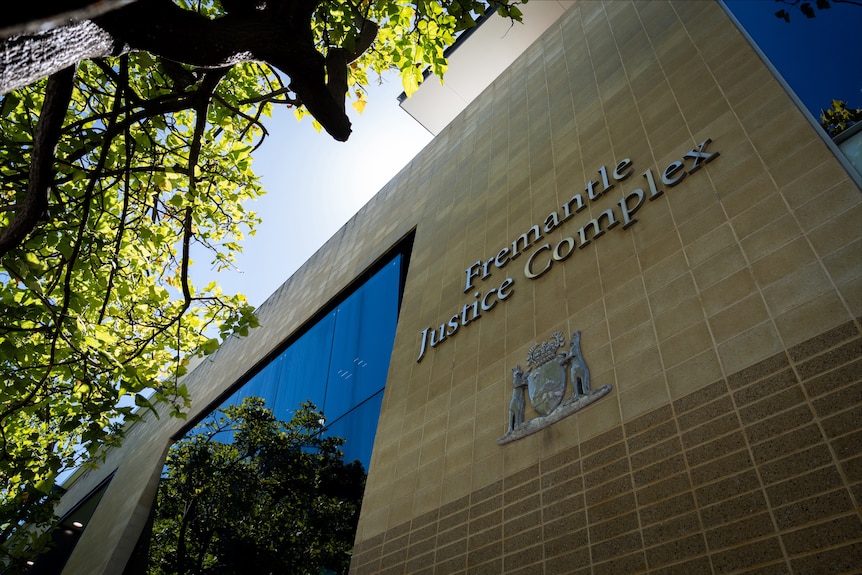 A photo of a sign stating 'Fremantle Justice Complex' on the side of a building