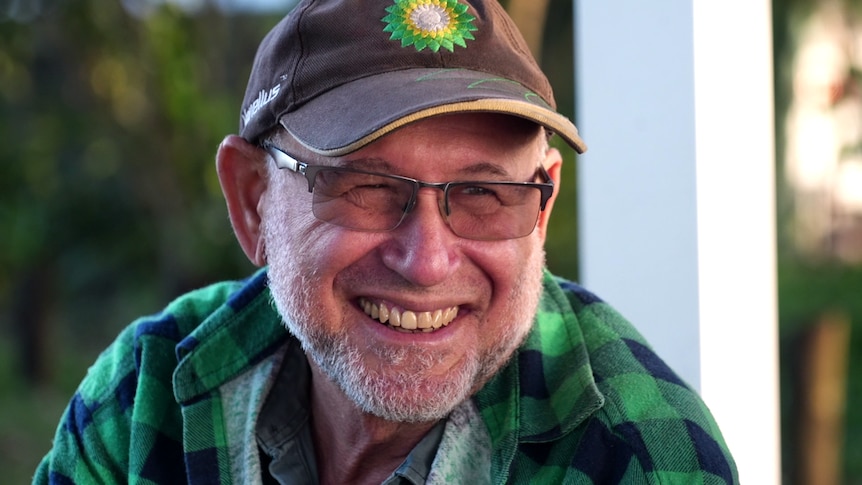 A man wearing a baseball cap laughing.
