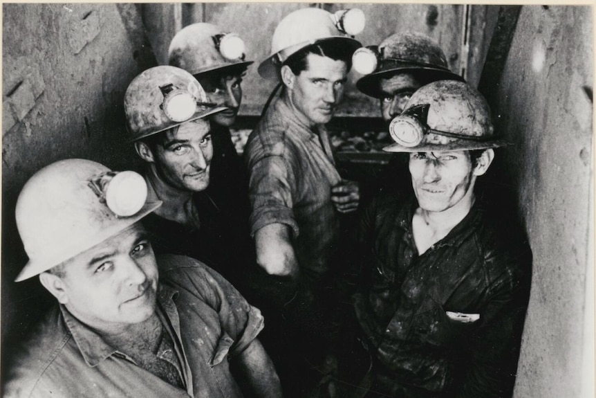 A group of underground miners in a mine shaft. 