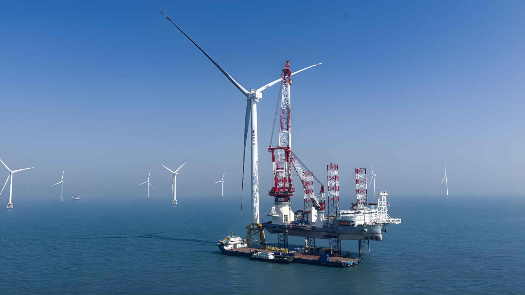 Massive offshore wind turbine being installed at sea near Hainan, with other turbines visible in the distance.