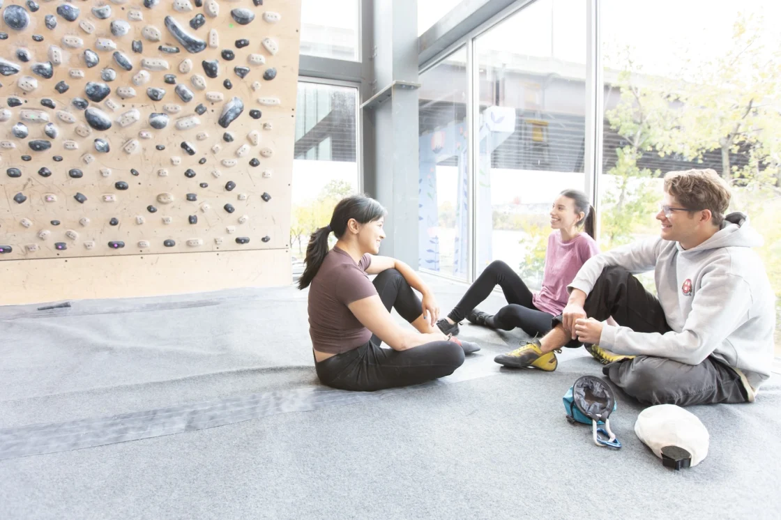 people sit together next to a rock climbing wall