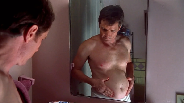 Hal wears nothing but white tightie-whities as he inspects his gut in the mirror in 