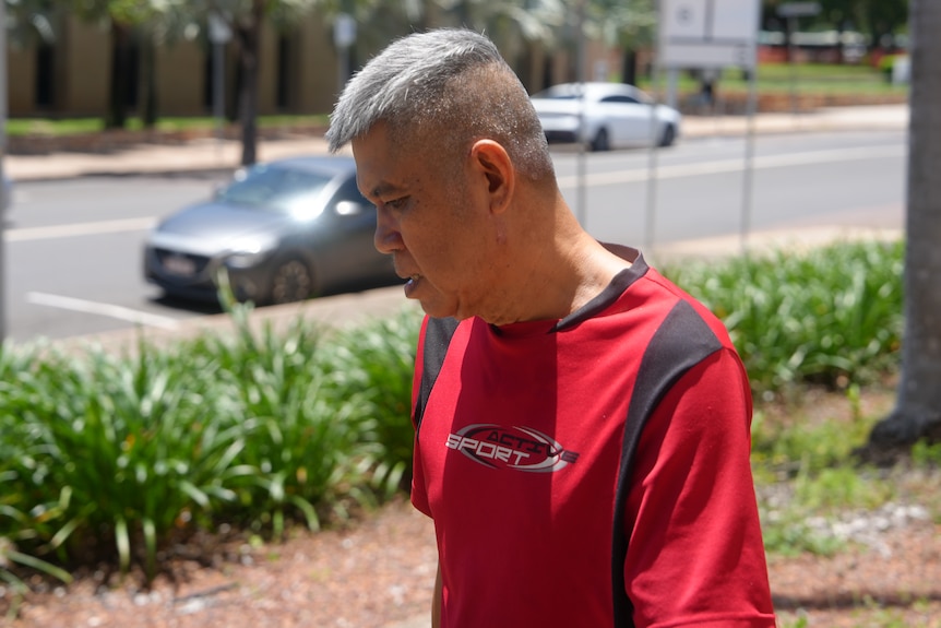 A Thai-Australian man in a red shirt, walking away from the court.