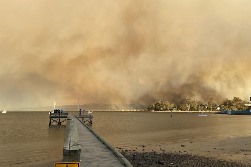 Onlookers watch the bushfire burning at Dianas Basin from across the bay at St Helens.