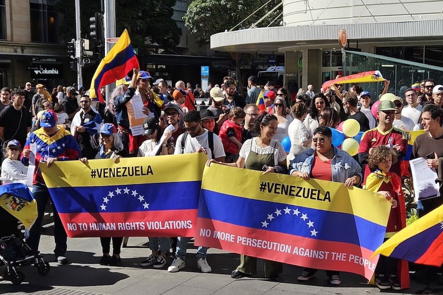 A crowd of people holding flags, balloons, and signs reading "NO MORE HUMAN RIGHTS VIOLATIONS".