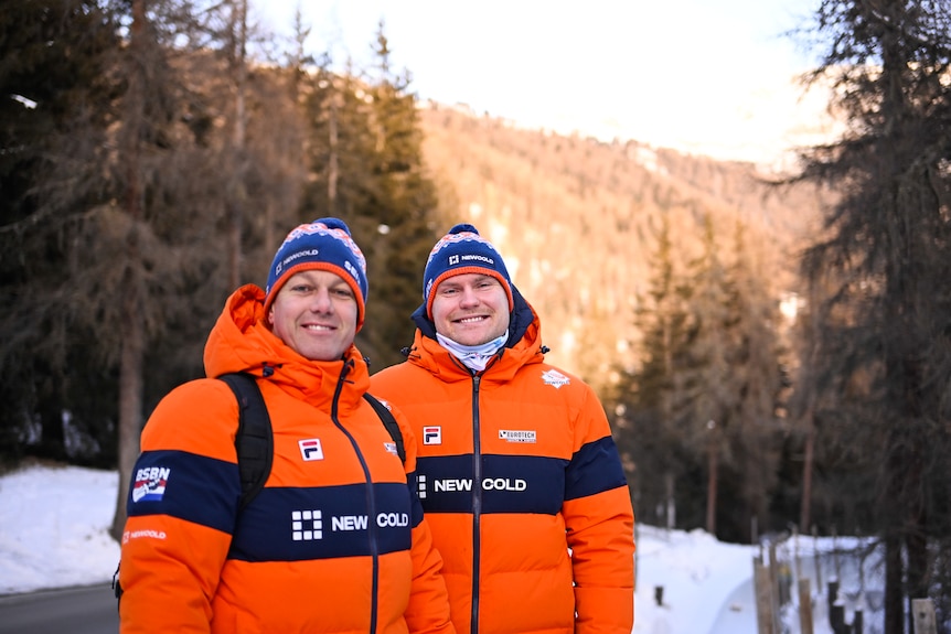 Dave Wesselink and Jelen Franjic smile for the camera wearing matching orange snow jackets and blue beanies. 
