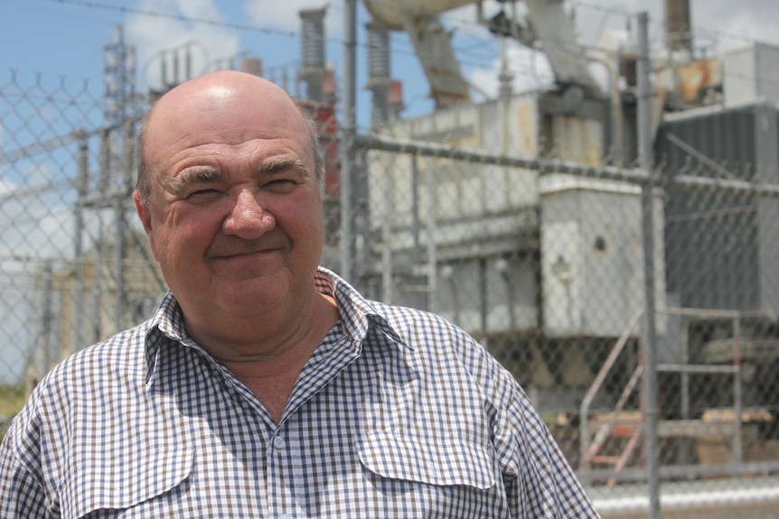 An older man with a bald head wearing a shirt smiling.