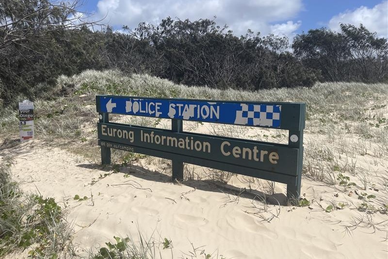 A sign reading 'police station' in the sand